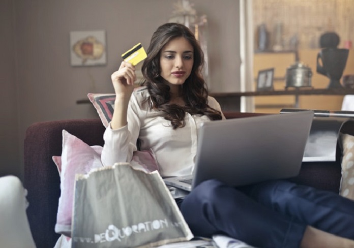 woman holding credit card in front of laptop